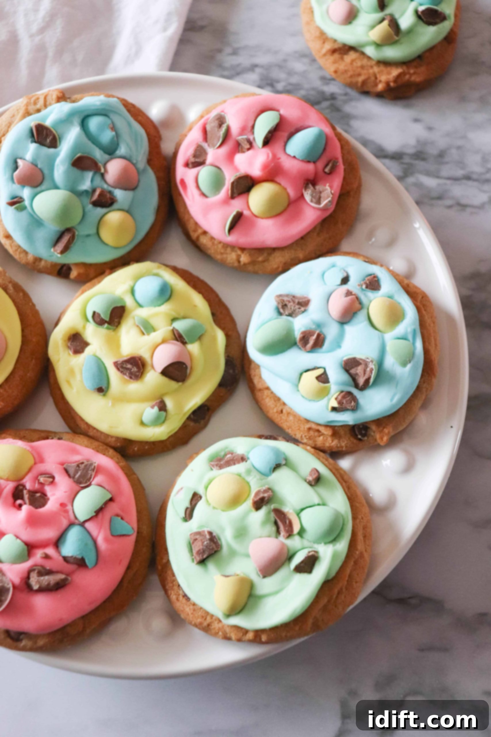 A platter of beautifully decorated Chocolate Chip Mini Egg Cookies with colorful icing and chopped Mini Eggs.