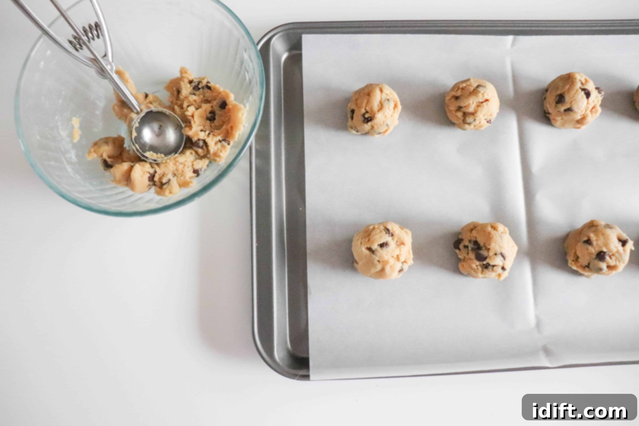 Scooped cookie batter on a baking sheet lined with parchment paper