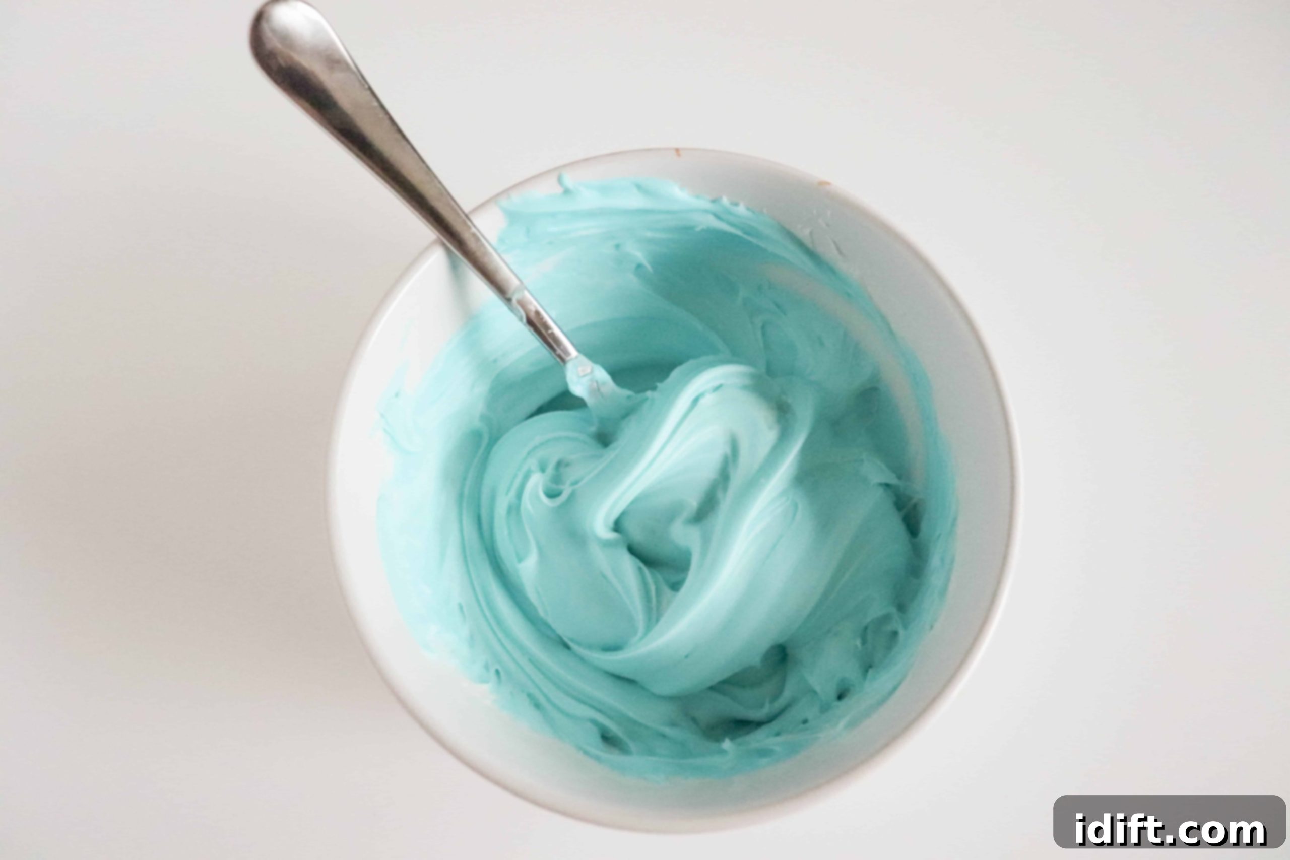 Tinted frosting in small bowls ready to decorate mini egg cookies