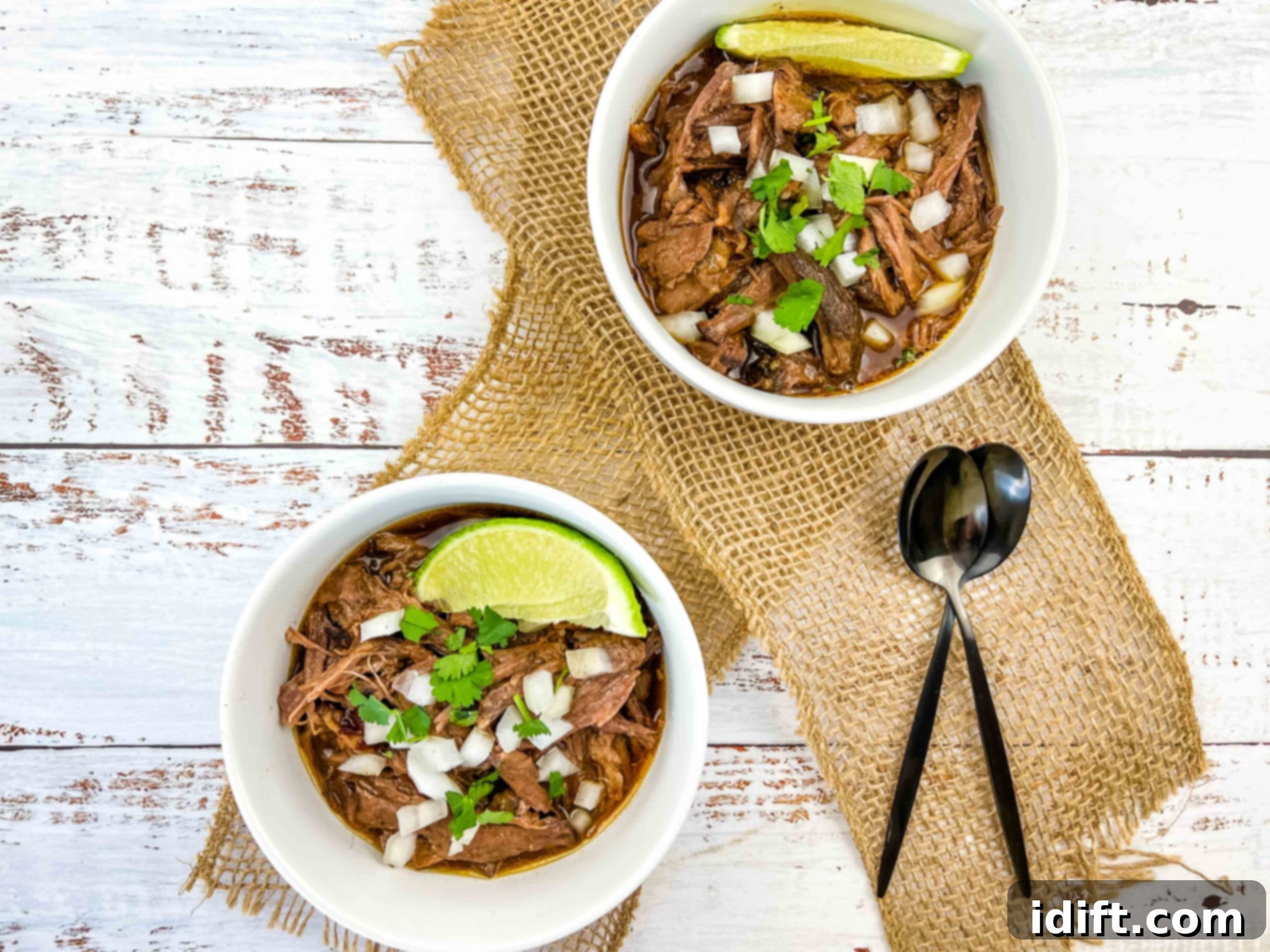 Tender Slow Cooker Birria de Res 8 Two bowls of birria de res garnished with lime wedges and cilantro.