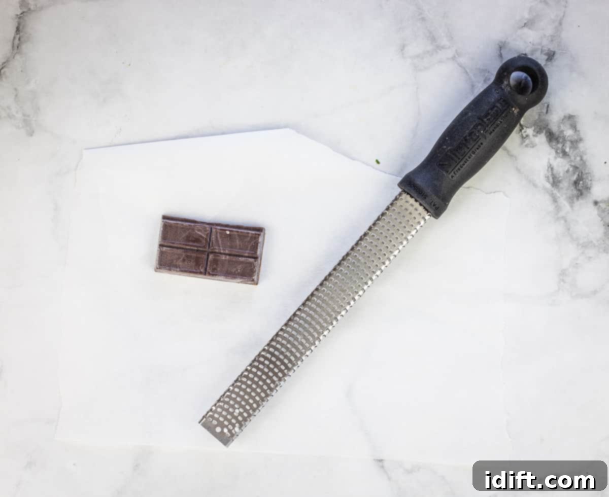 A bar of semi-sweet chocolate next to a microplane grater, preparing for making chocolate shavings.