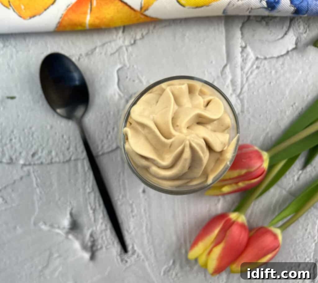 A single glass dessert cup filled with light and airy dulce de leche mousse, garnished with delicate chocolate shavings, ready to be enjoyed.