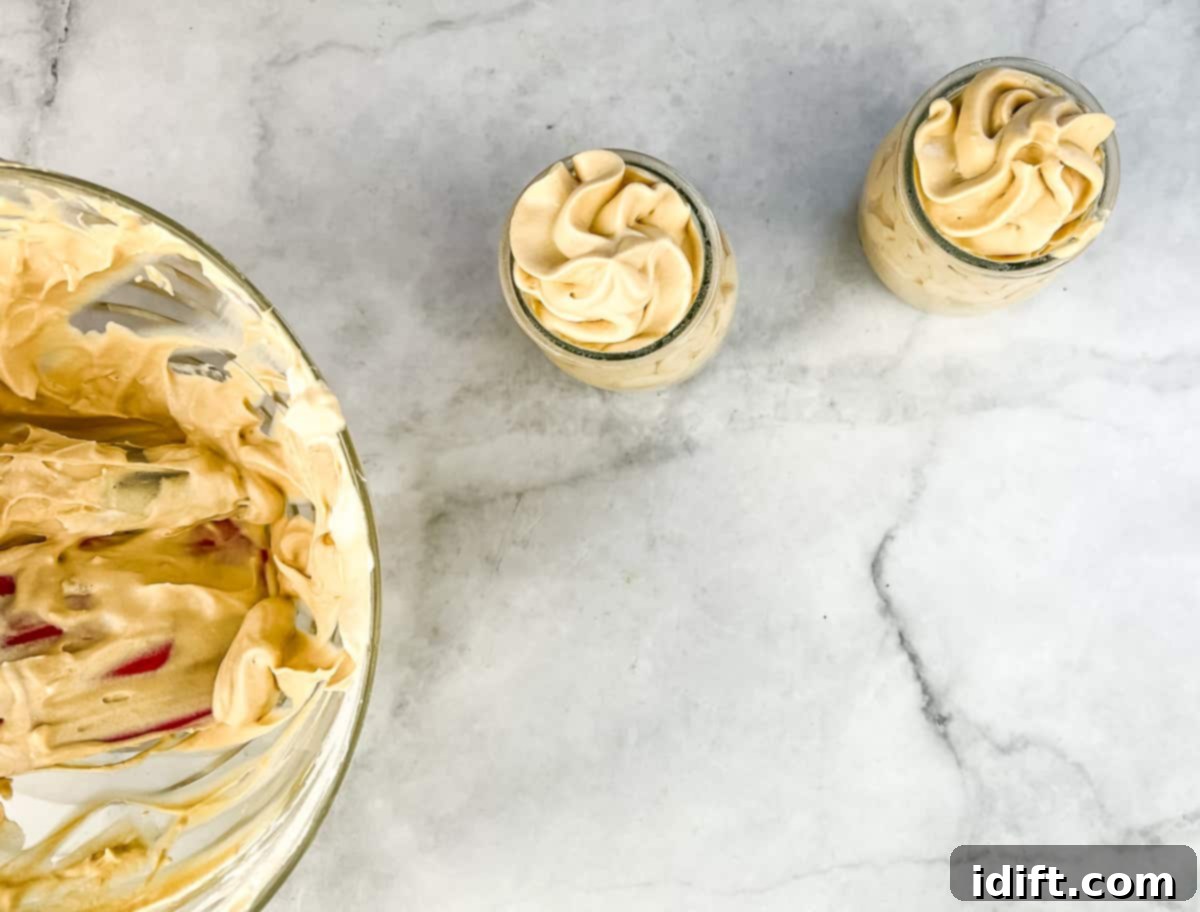 Two dessert cups beautifully filled with the finished Dulce de Leche Mousse, ready for chilling.