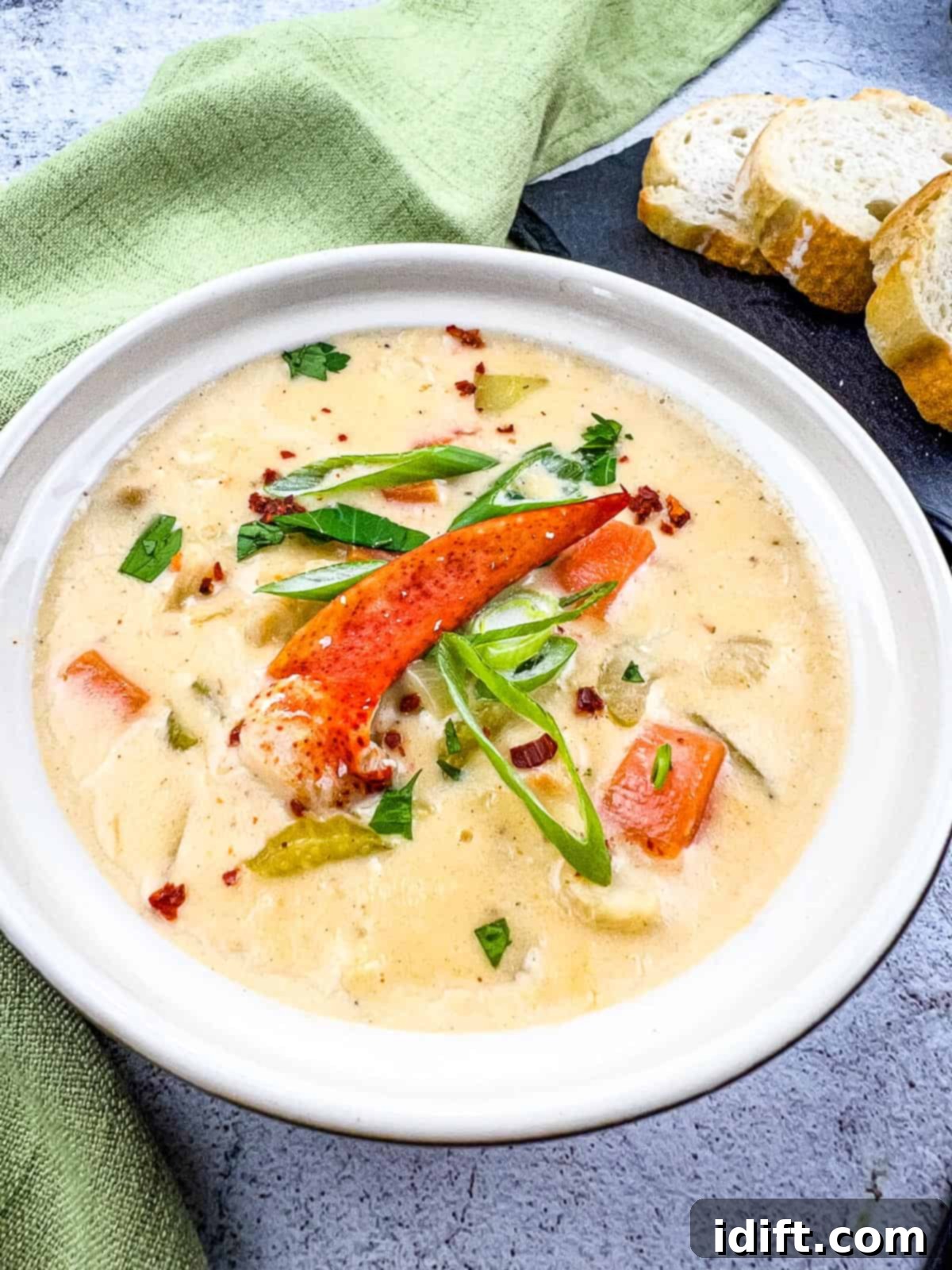 A steaming bowl of rich lobster chowder, garnished with fresh herbs and served alongside crusty bread, ready to be enjoyed.