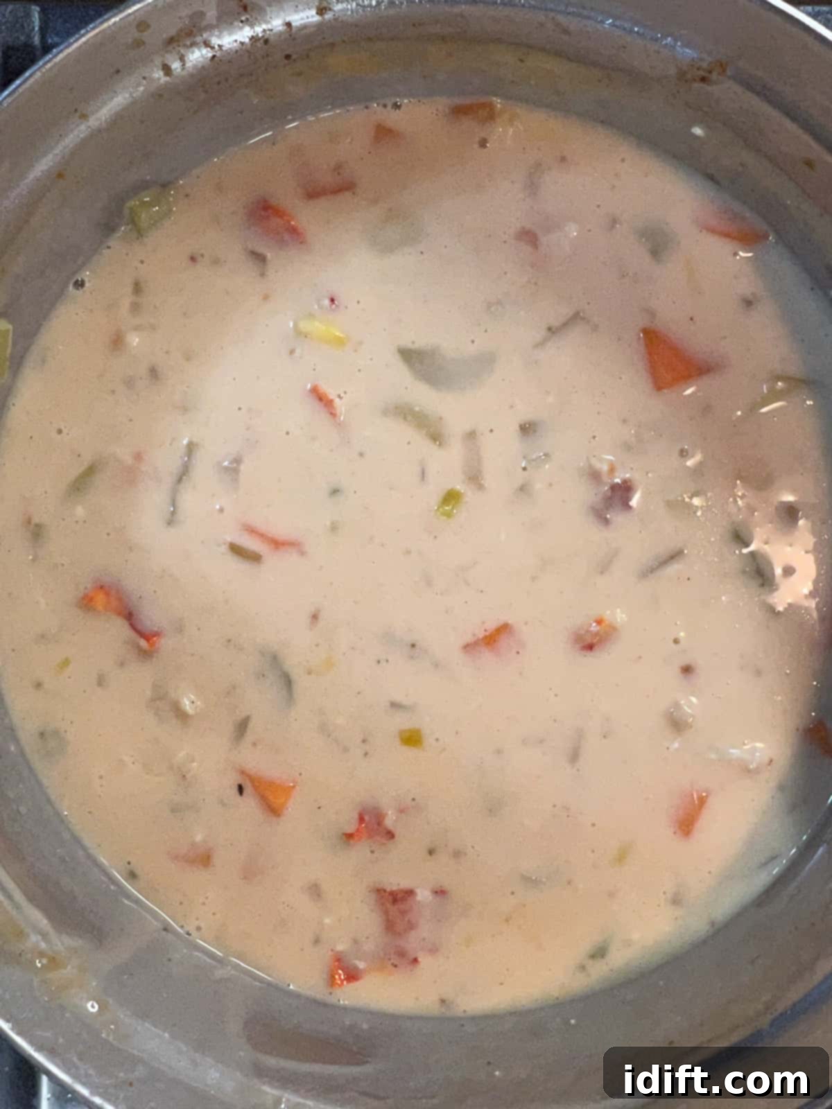 Corn, diced potatoes, heavy cream, and cooked lobster meat added to the simmering chowder, blending to create the final dish.