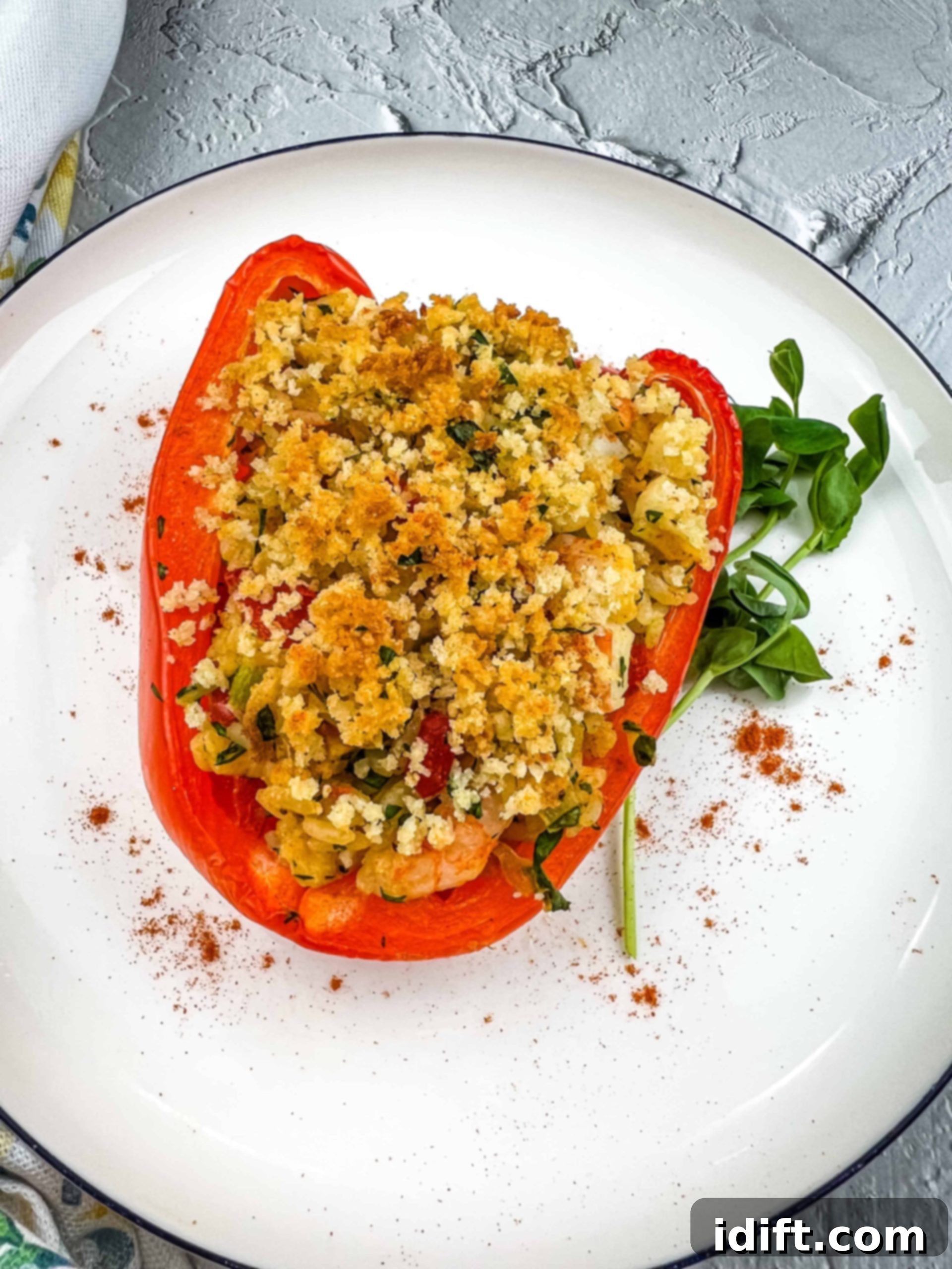 Seafood stuffed bell pepper on a plate, garnished with fresh herbs