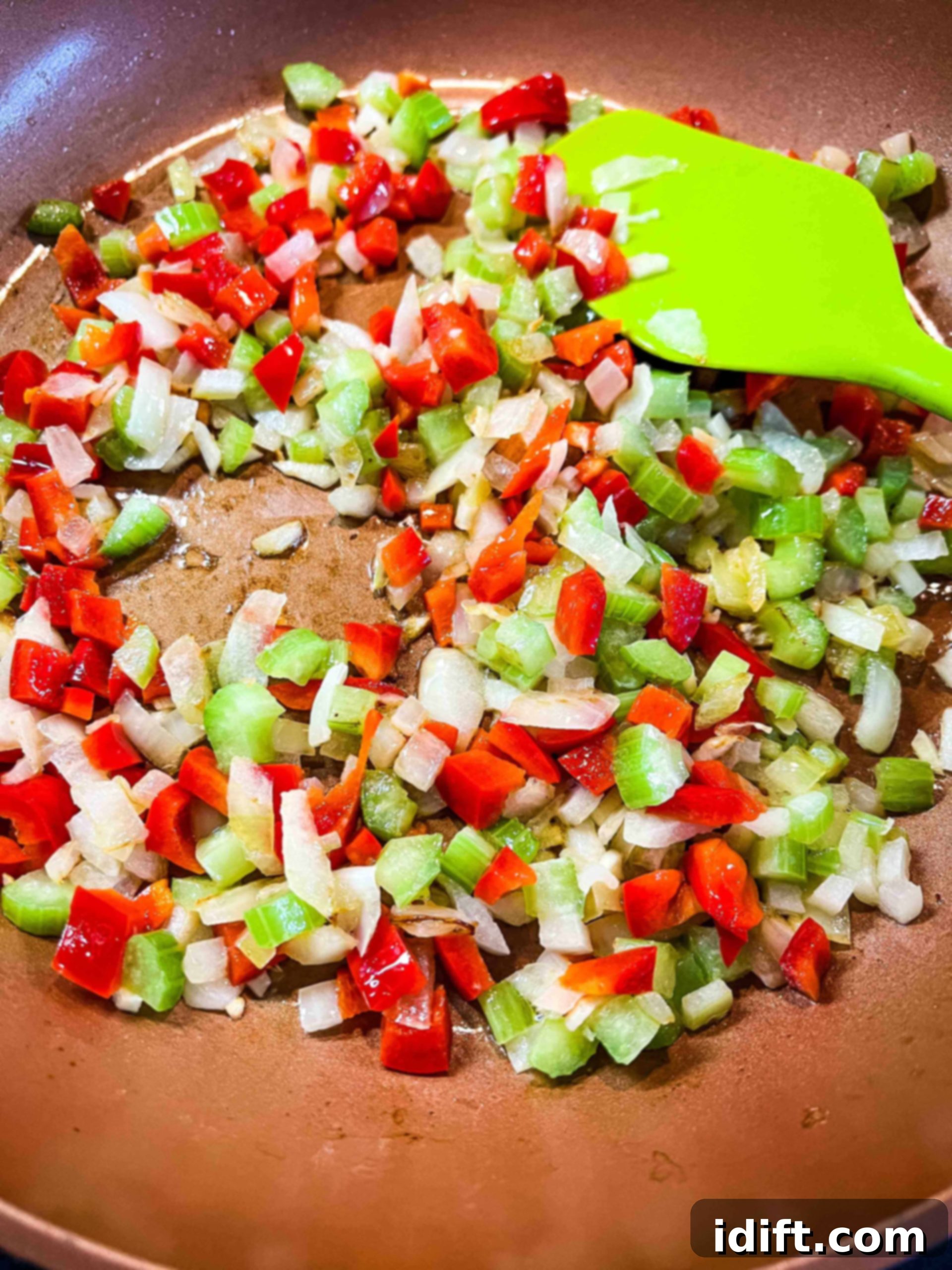 Onion, celery, and bell pepper sauteeing in a skillet until tender