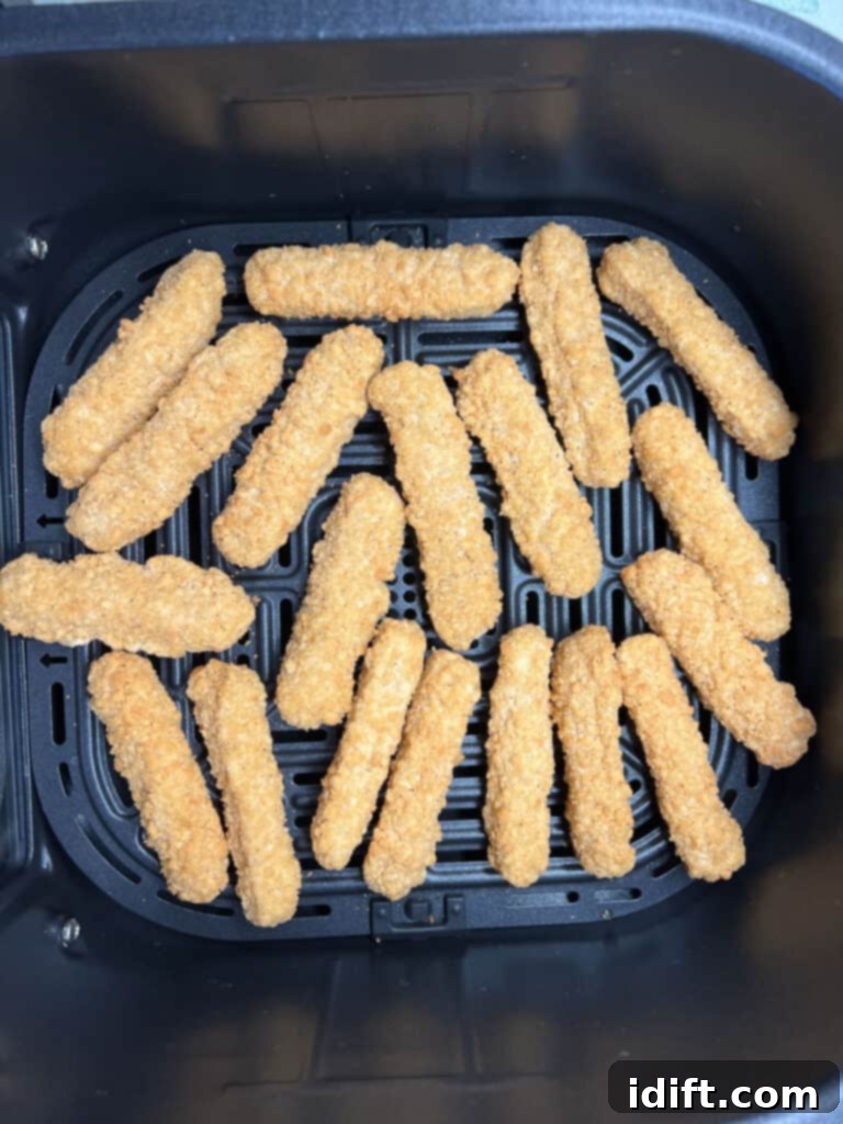 Crispy Air Fryer Chicken Fries 3 Frozen chicken fries being placed into an air fryer basket