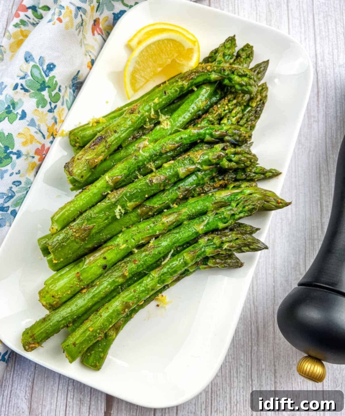 Perfectly Seared Blackstone Asparagus 2 Freshly griddled asparagus spears served on a pristine white platter, garnished with bright yellow lemon wedges, ready to be enjoyed as a perfect side dish.