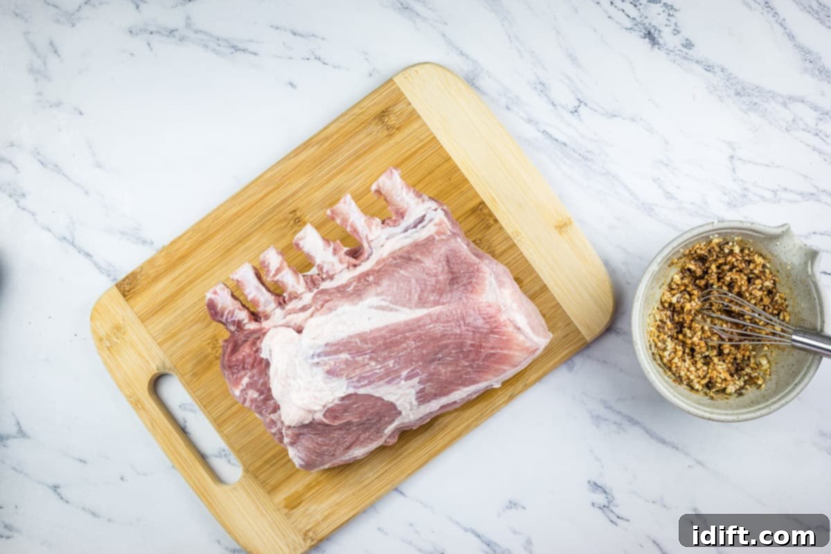 Slow-Smoked Pork Rack 6 raw rack of pork next to a bowl of the garlic rub, ready for application