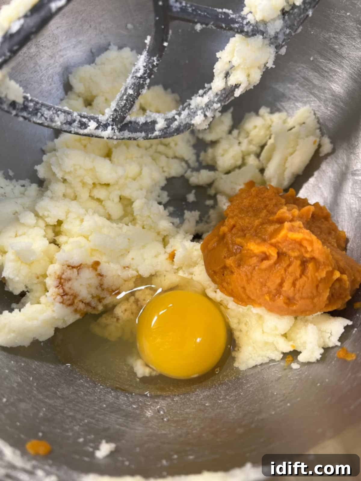 Adding egg and pumpkin puree to the creamed butter and sugar mixture.