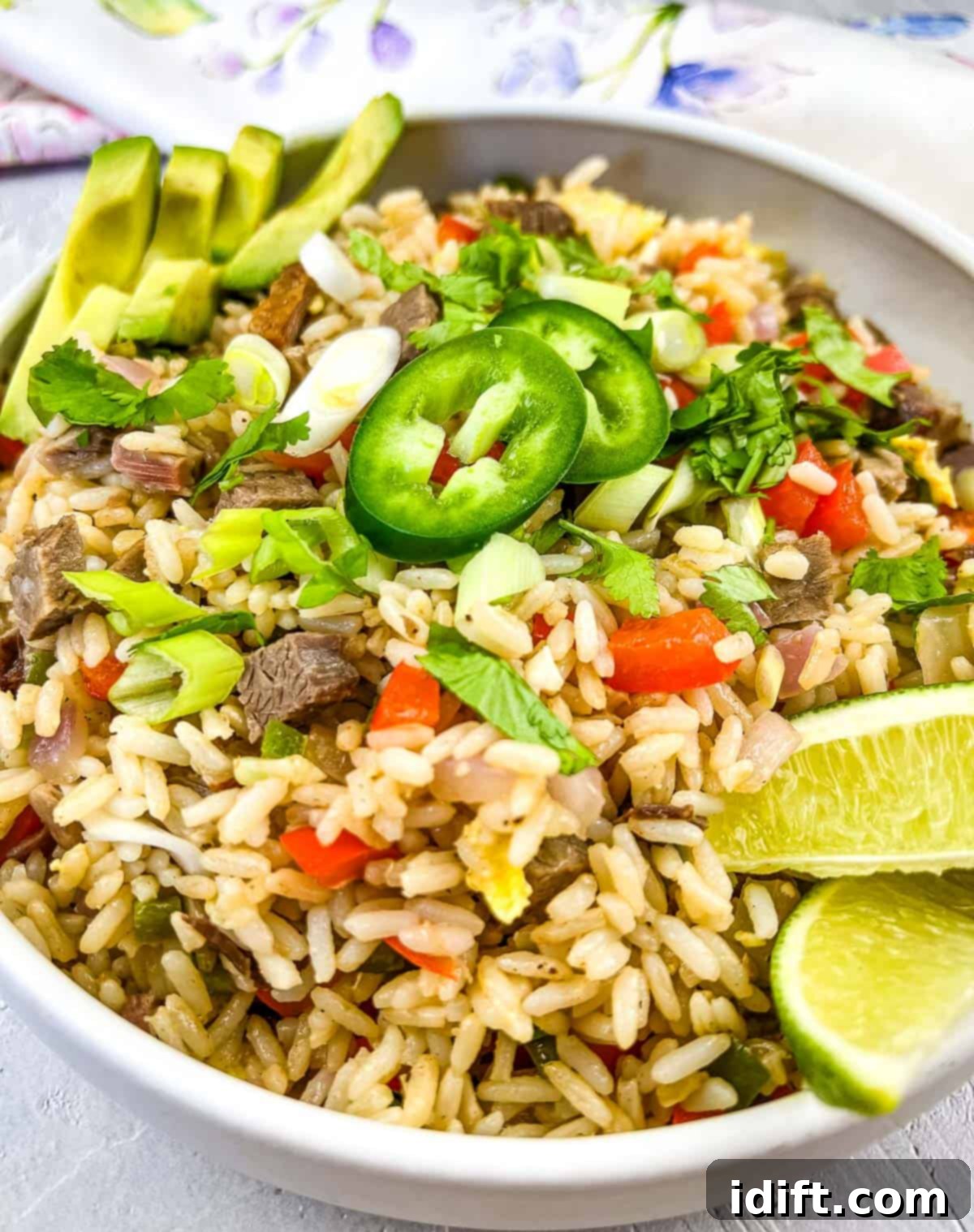 Delicious Brisket Fried Rice served in a pristine white bowl, garnished with fresh green onions and cilantro, ready to be enjoyed.
