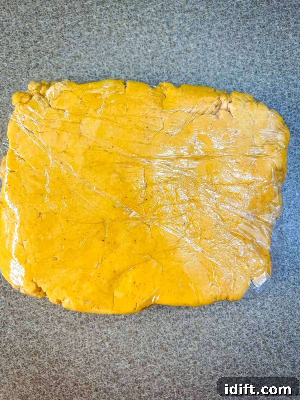 Cheez-It dough wrapped in plastic wrap, ready for chilling in the refrigerator.