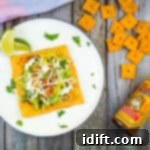 cheez-it tostada on a plate with crackers and hot sauce nearby