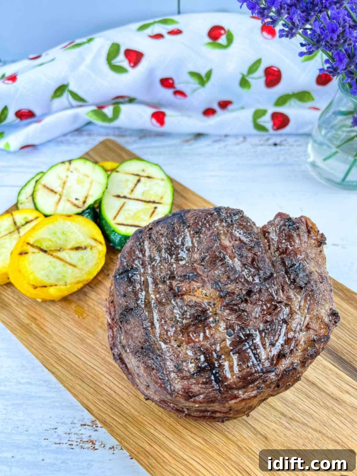 grilled ribeye cap steak on a board with grilled veggies