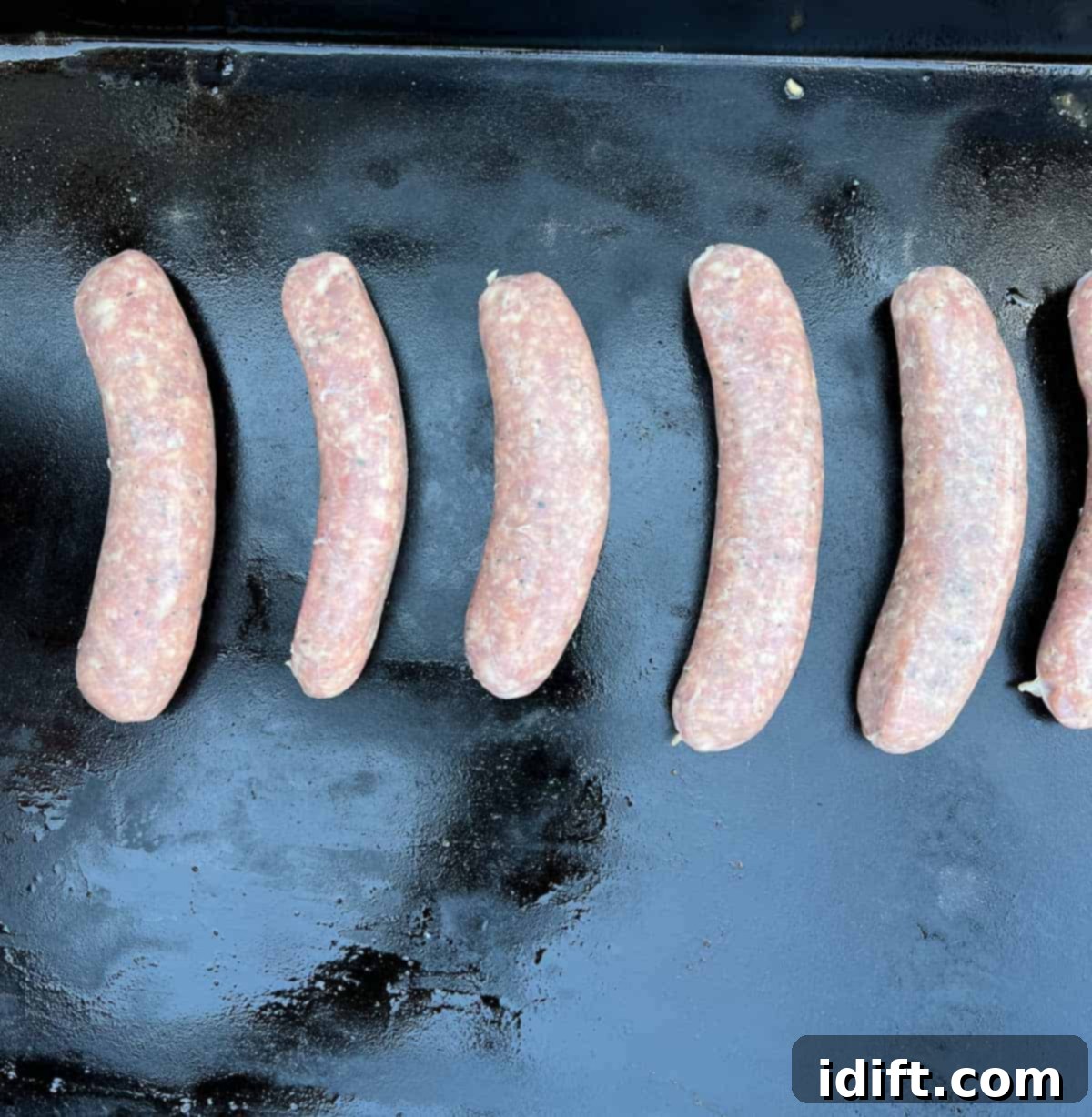 Raw sausages placed on a lightly oiled Blackstone griddle
