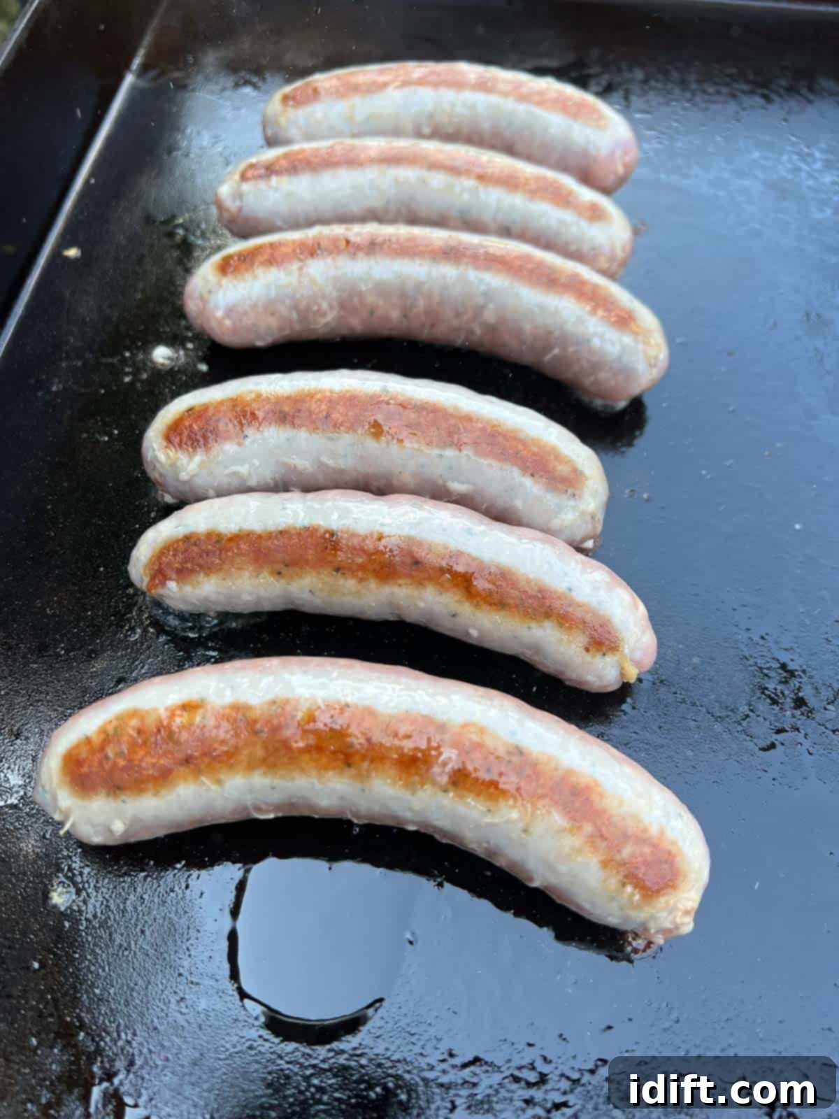 Sausages browning evenly on all sides on the Blackstone griddle