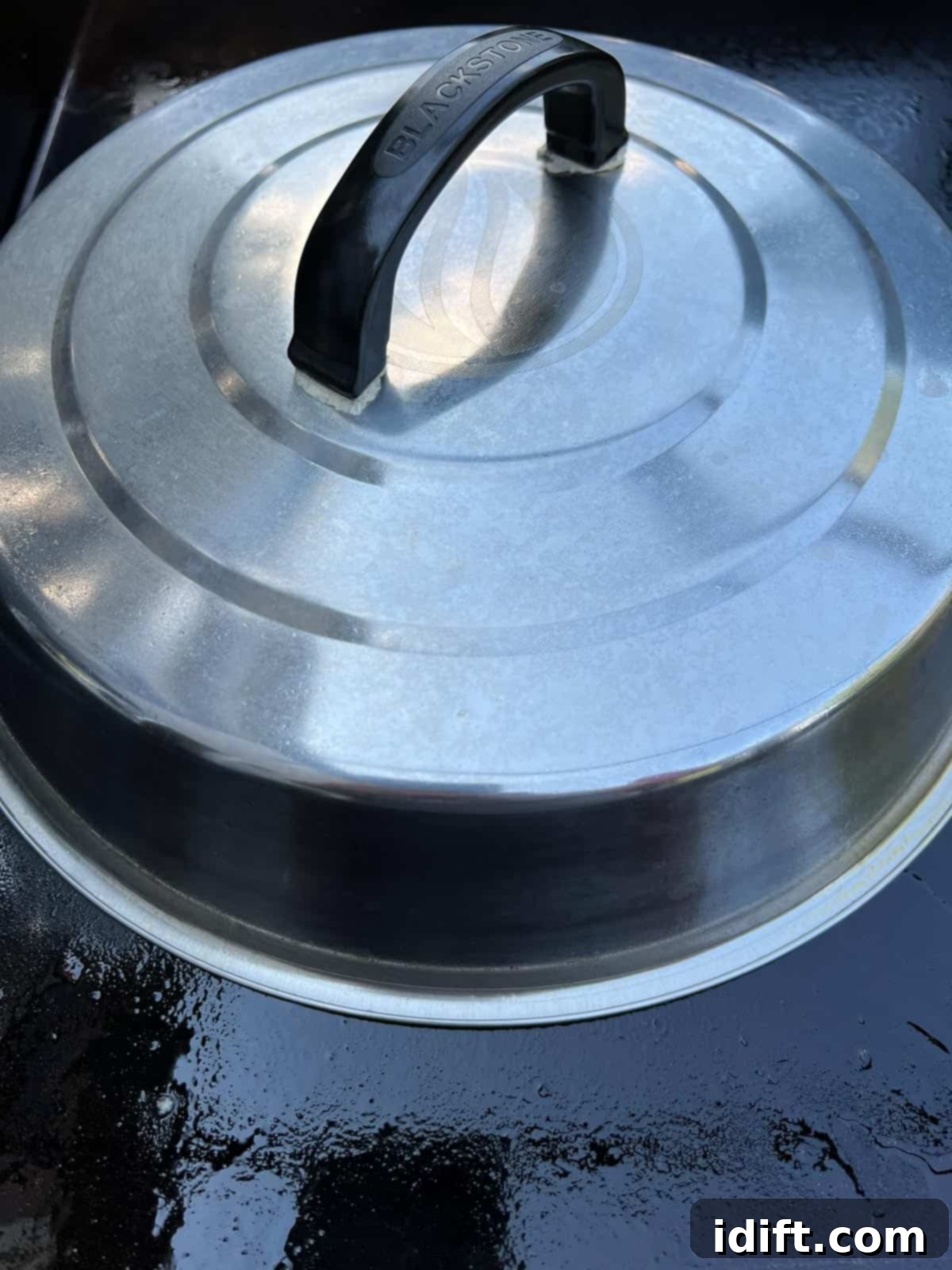 Sausages steaming under a cooking dome on the Blackstone griddle