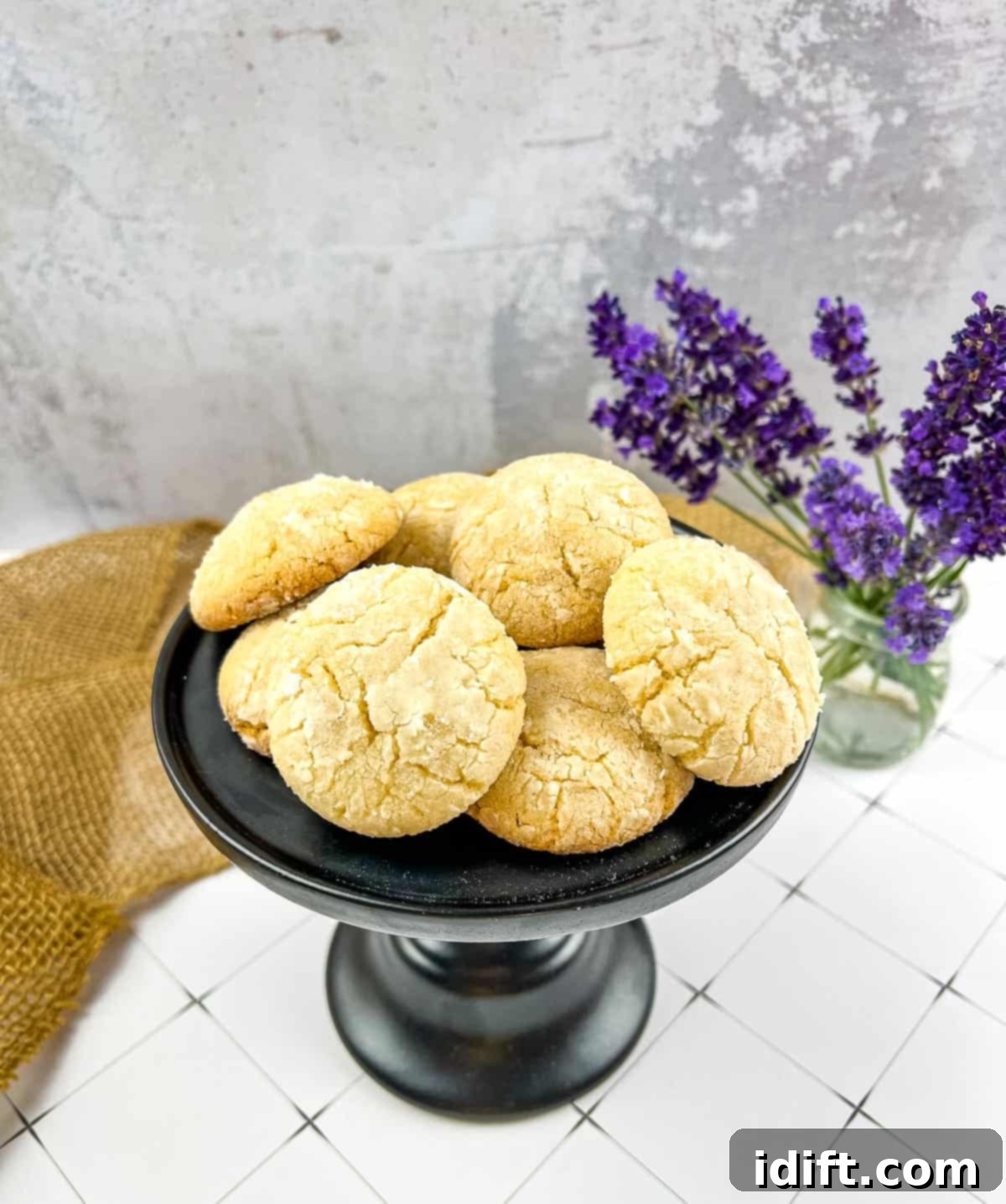 white chocolate crinkle cookies on a pedestal with laveneder in the background
