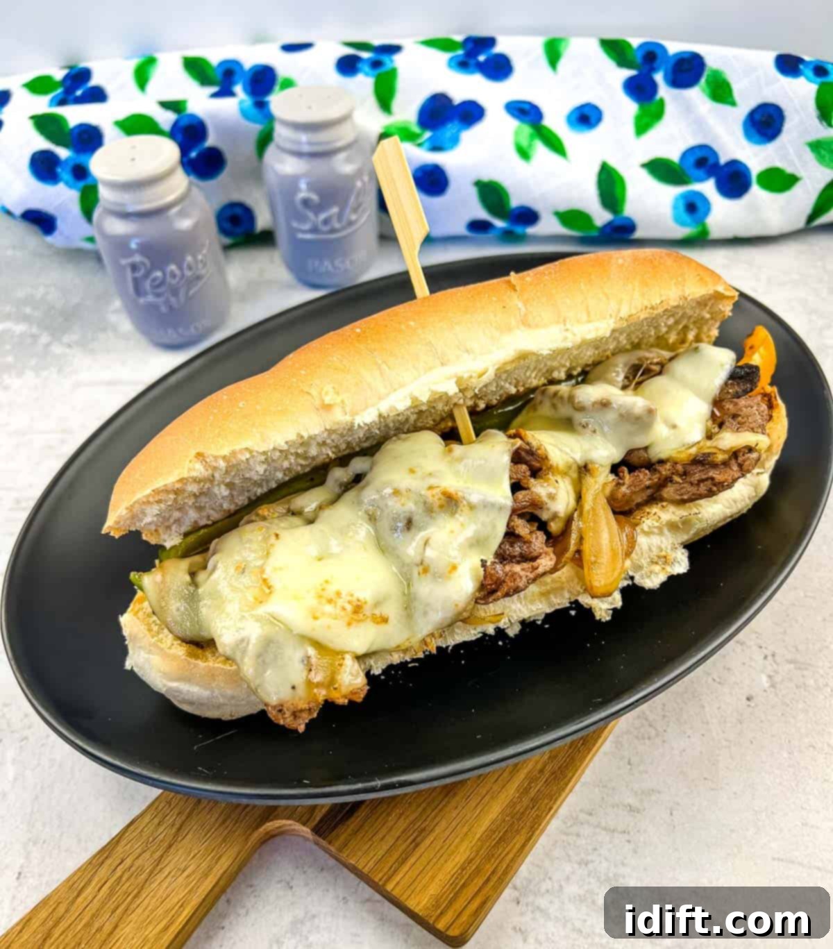 A perfectly cooked Blackstone Philly Cheesesteak sandwich on a dark plate, showcasing melted cheese and succulent ingredients.