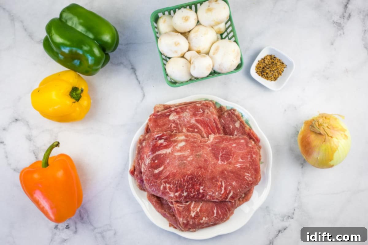 All the fresh ingredients laid out for making blackstone philly cheesesteaks, including shaved beef, onions, peppers, mushrooms, and cheese.