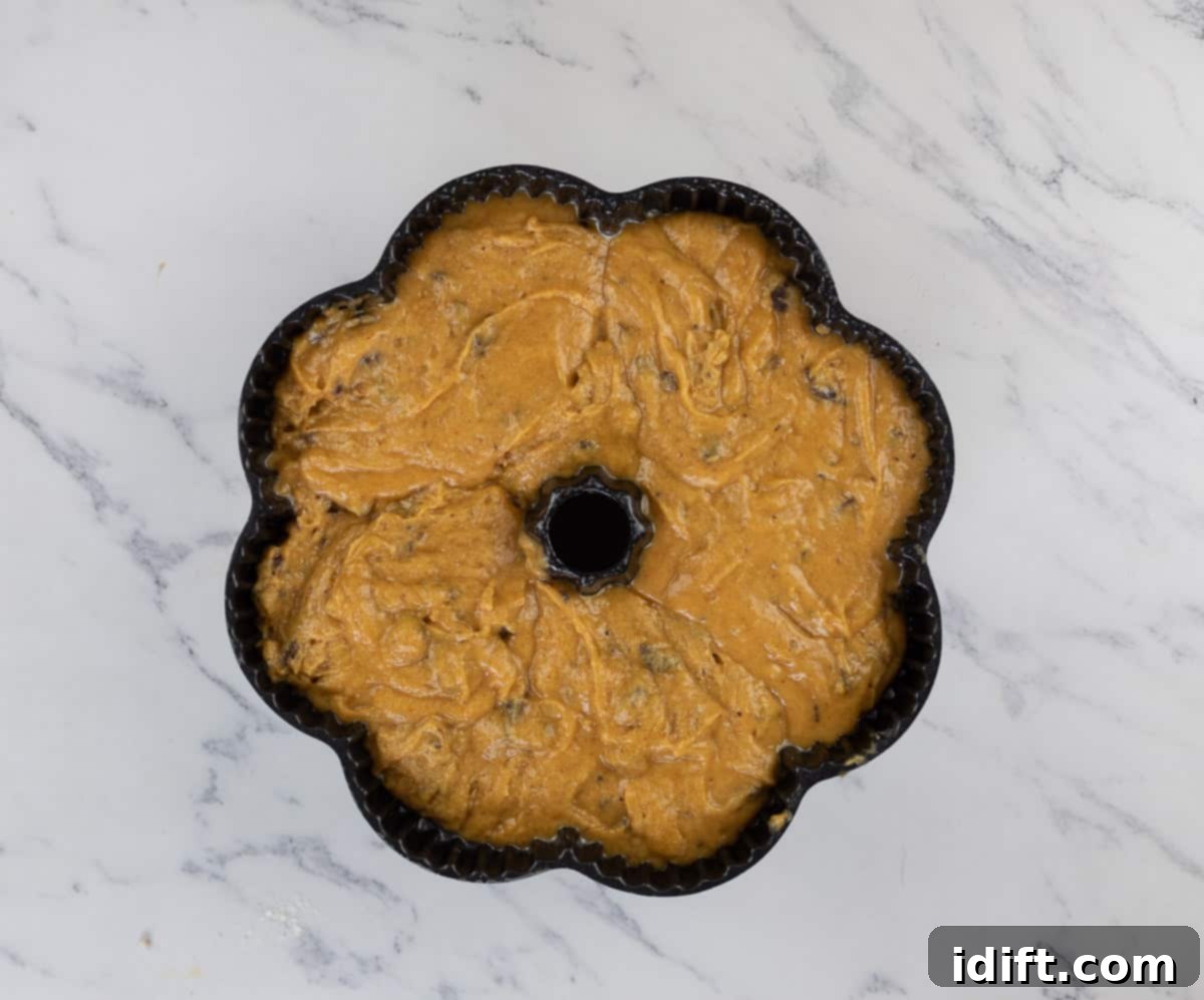 Spiced Chocolate Pumpkin Dream 9 Pouring pumpkin chocolate cake batter into a greased bundt pan