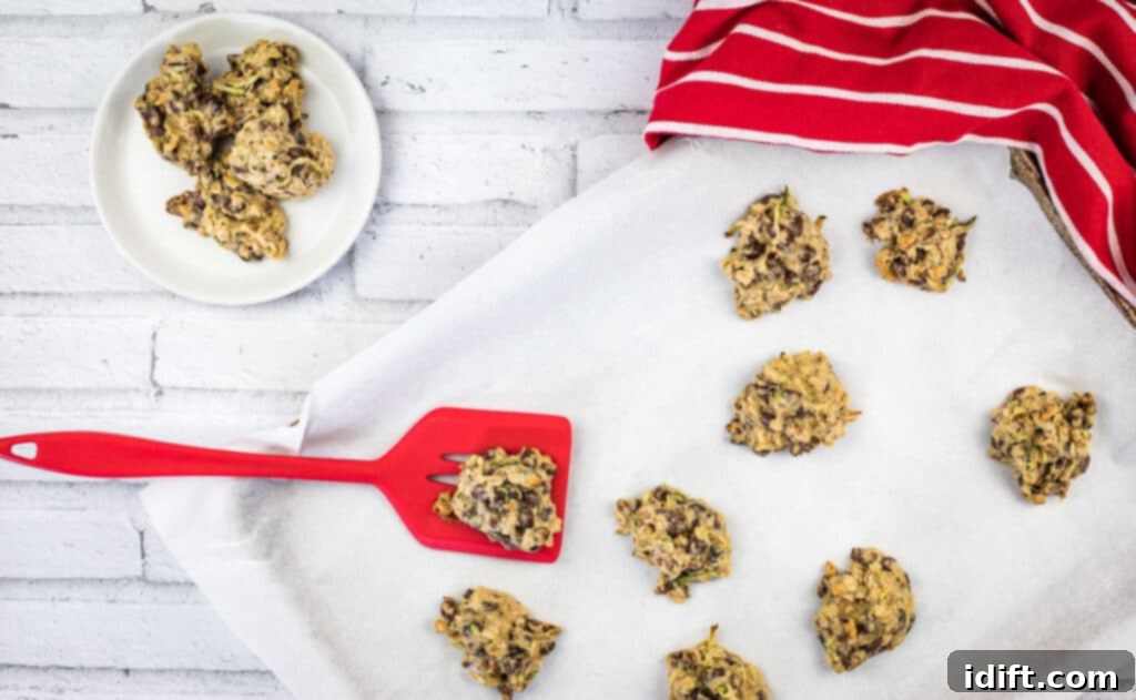 Freshly baked zucchini cookies with chocolate and pecans cooling on a baking sheet, ready to be transferred.