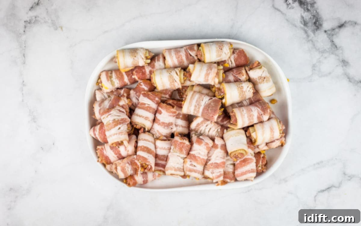 A plate showcasing rigatoni noodles meticulously wrapped in strips of bacon, ready for the next step.