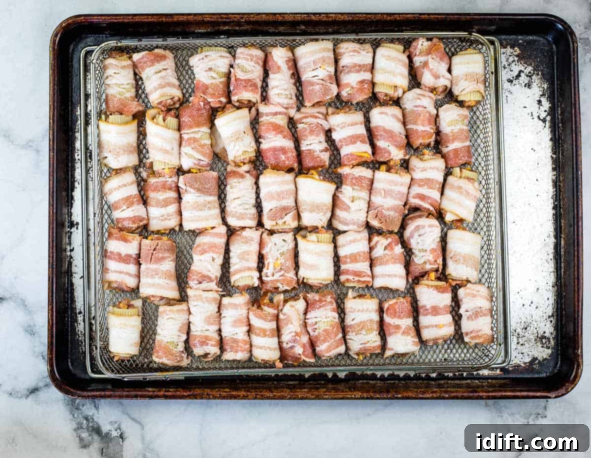 Prepared bacon-wrapped bullets neatly arranged on a wire rack, poised for smoking.