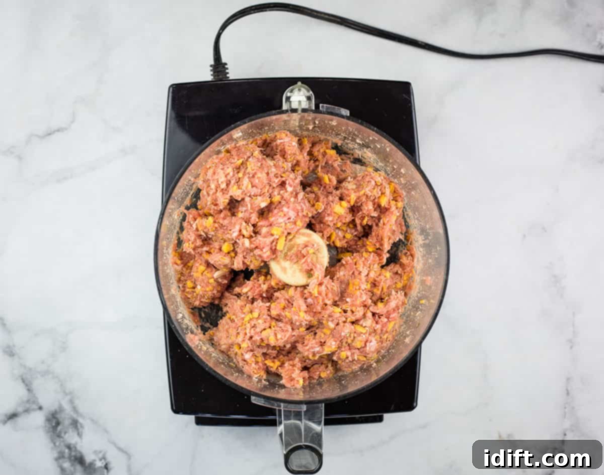 The process of pulsing meat, cheese, and spices together in a food processor for the bullet filling.