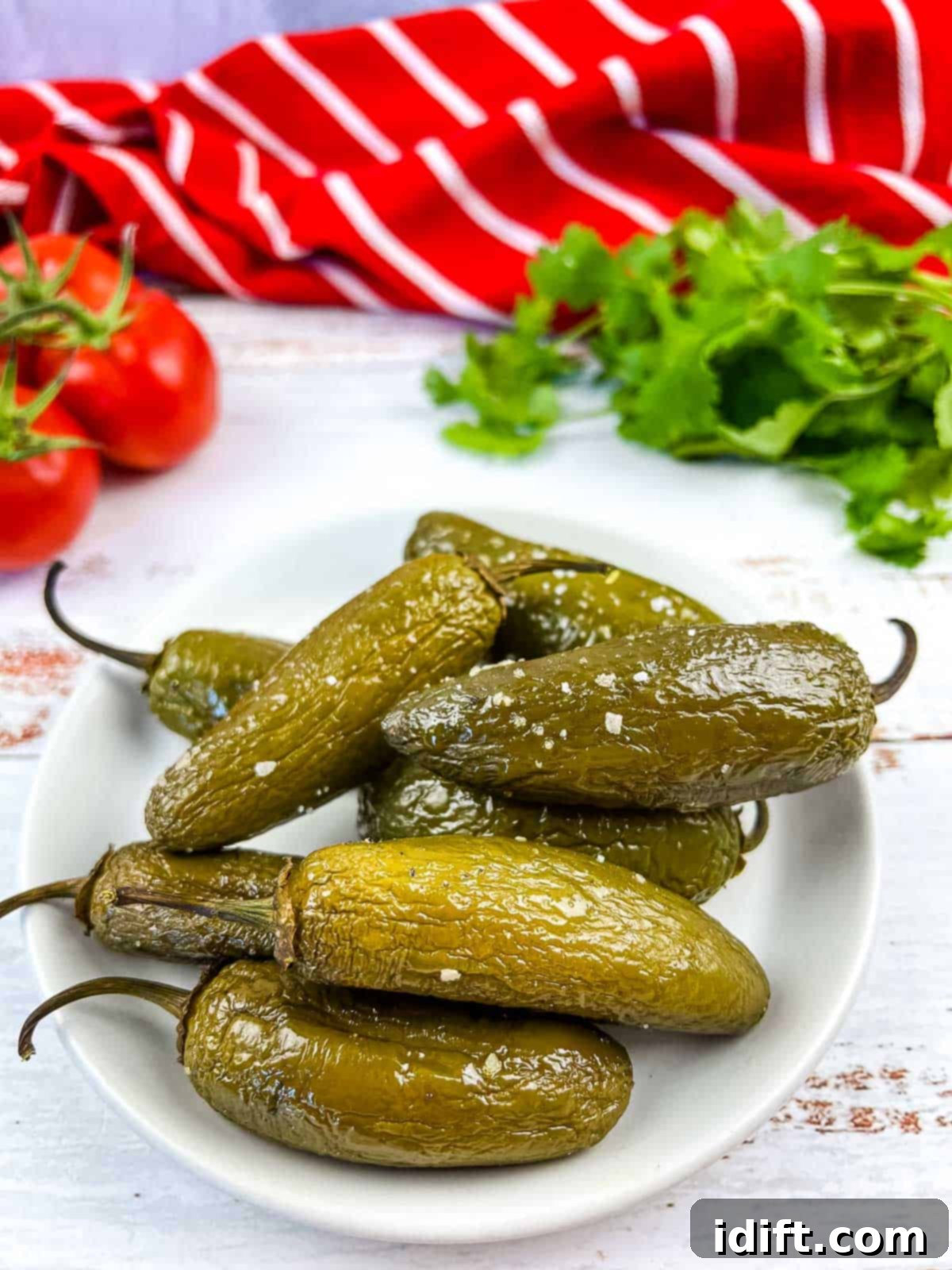 Ember-Kissed Jalapeños 2 Perfectly smoked jalapenos resting on a pristine white plate, showcasing their vibrant green color and inviting char marks.