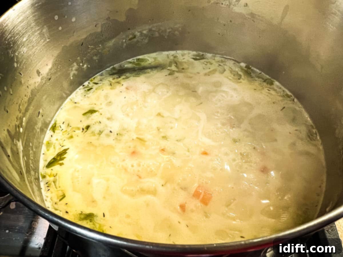 Soup simmering with diced potatoes to cook until tender.