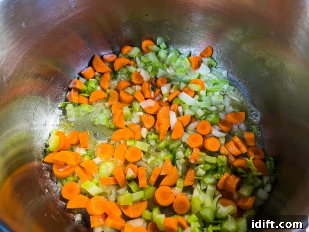 Sautéing the diced vegetables in a large pot.
