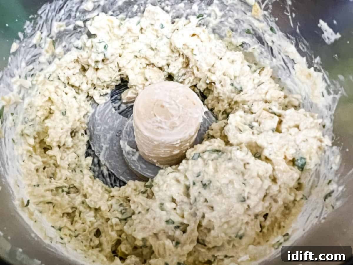 Creamy Jalapeno Artichoke Dream 7 The dip mixture pulsed in the food processor until it's chunky but well combined, showing a creamy texture with visible artichoke pieces.