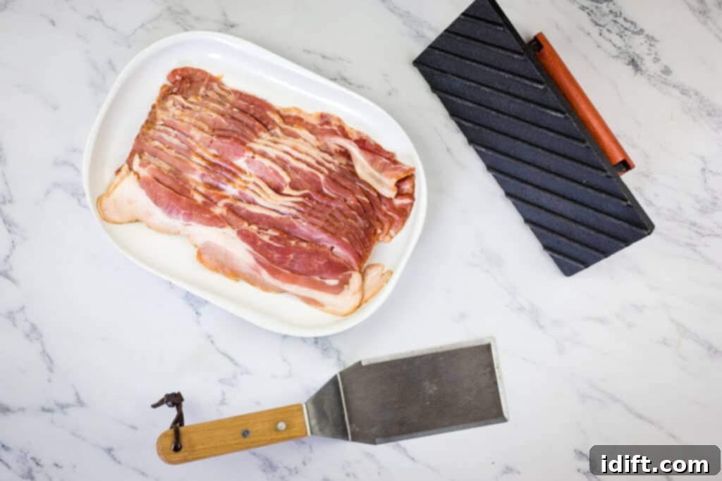 Blackstone Bacon Mastery: Achieve Crispy Perfection 4 Essential tools and ingredients laid out for making bacon on a Blackstone Griddle, including various types of bacon, tongs, and a griddle press.