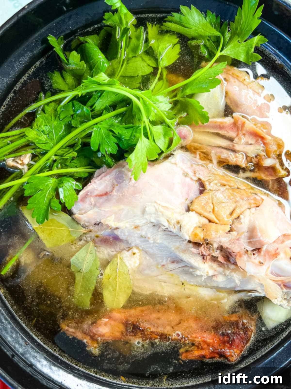 Turkey carcass, hot water, parsley, bay leaves, and peppercorns added to the Dutch oven.