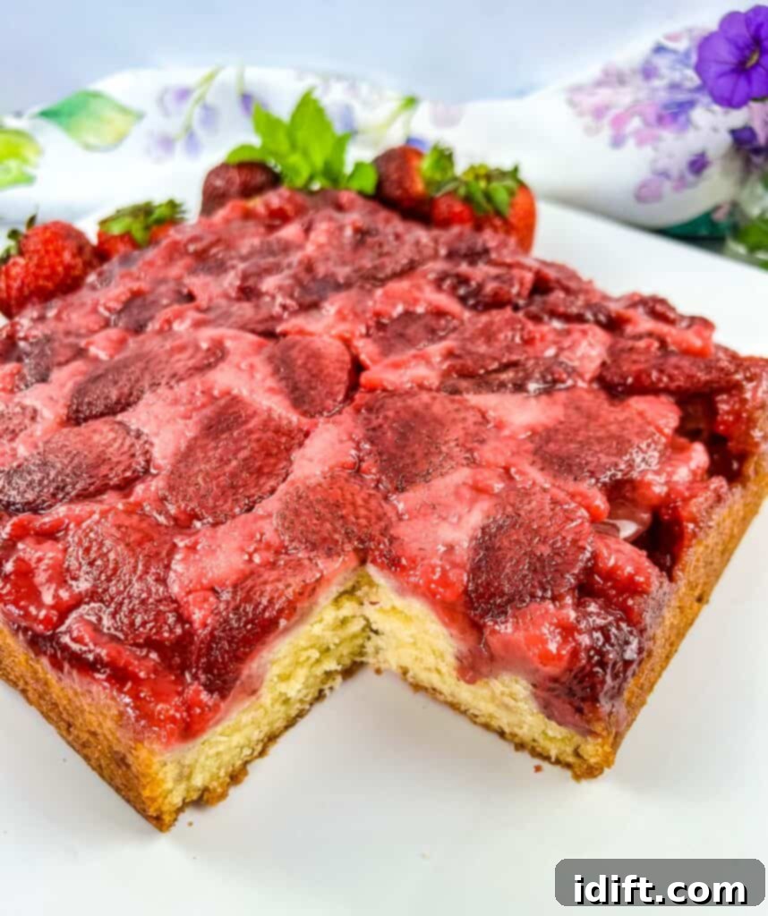 Strawberry Upside Down Cake on a plate with a slice cut out of it.