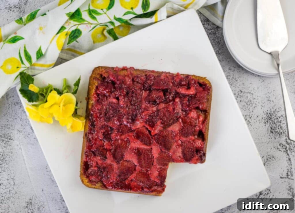 A top-down shot of Strawberry Upside Down Cake on a plate with a piece cut out of it.