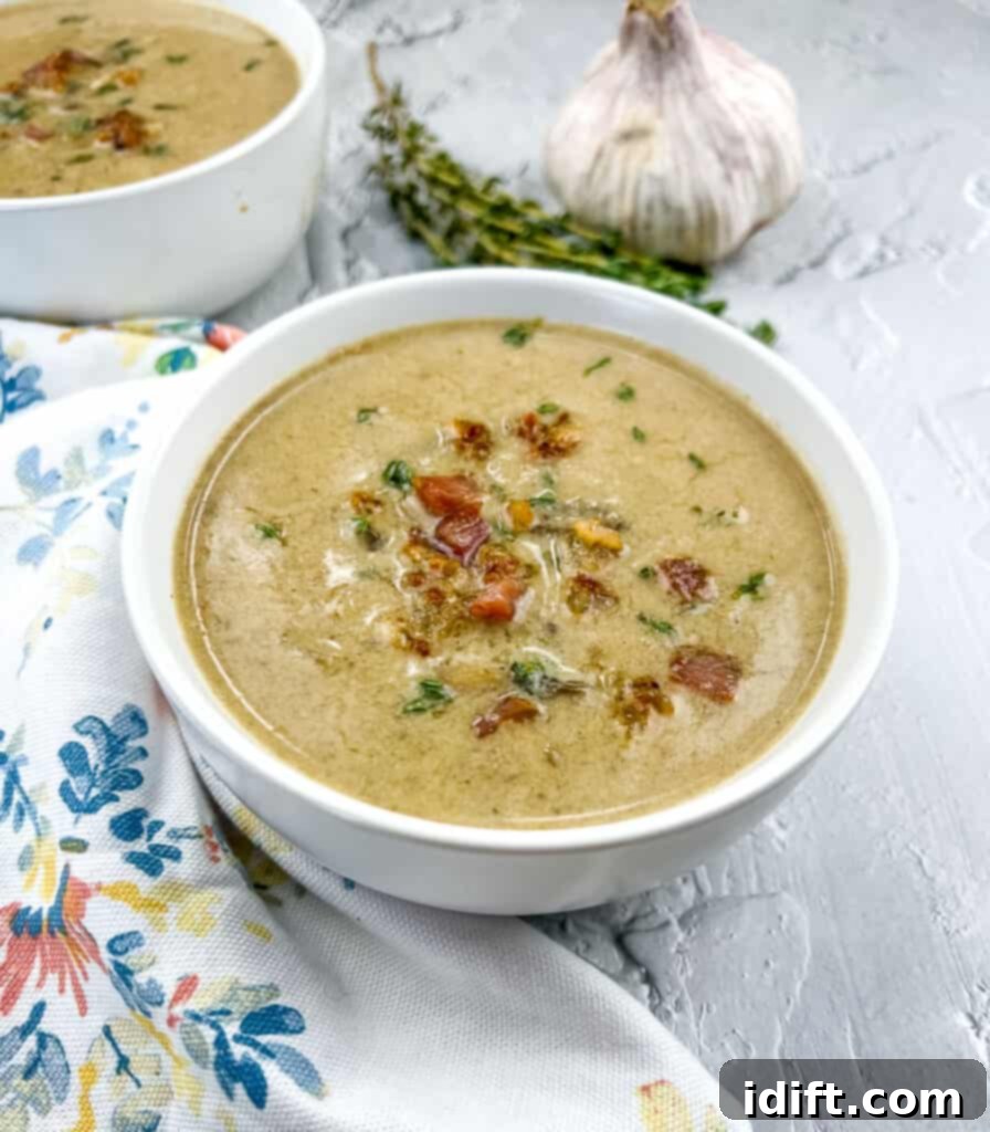 Sweet Caramelized Onion and Umami Mushroom Soup 2 A beautifully presented bowl of creamy Caramelized Onion and Mushroom Soup, with a second bowl softly blurred in the background, hinting at its inviting warmth.