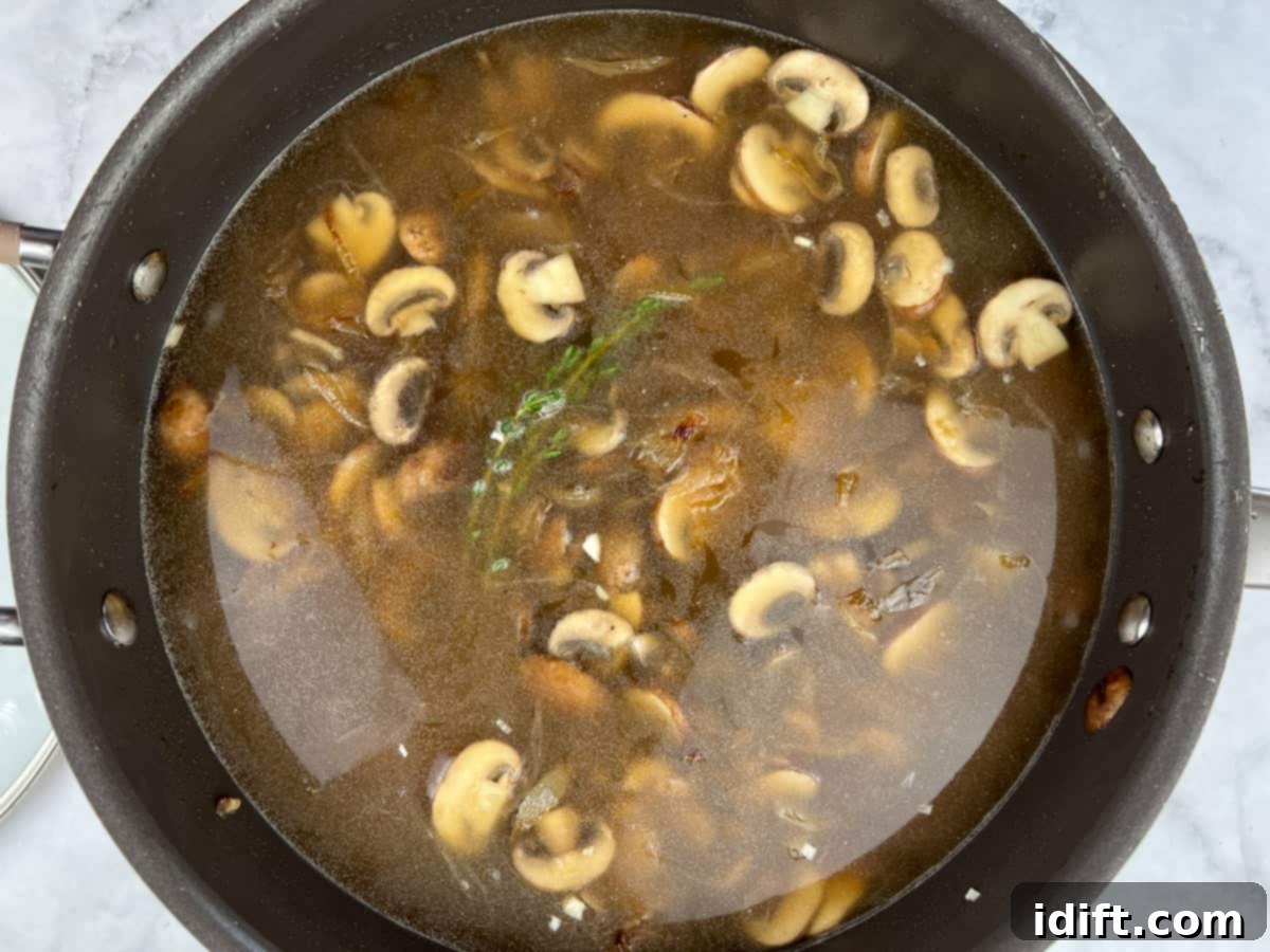 Sweet Caramelized Onion and Umami Mushroom Soup 10 Chicken and beef broths combined with the caramelized onions, mushrooms, and thyme sprigs in the pot, ready for simmering.