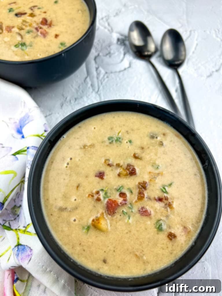 Sweet Caramelized Onion and Umami Mushroom Soup 5 A dark, elegant bowl filled with creamy Caramelized Onion and Mushroom Soup, perfectly garnished, with two spoons invitingly placed nearby.