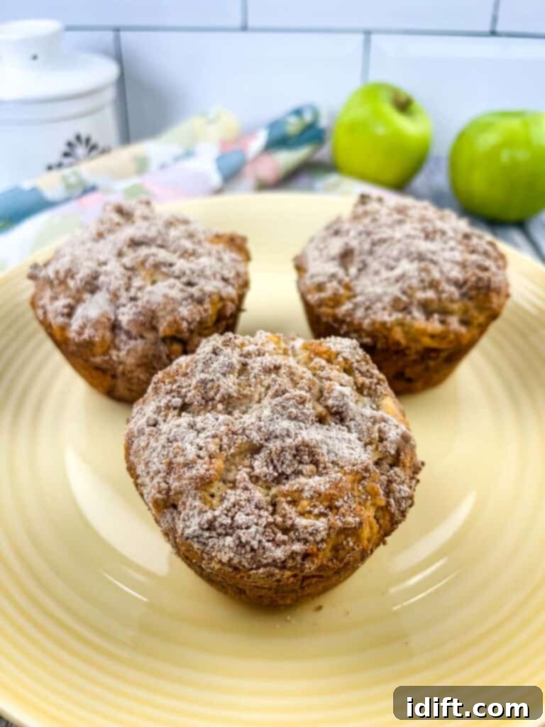 Wholesome Apple Date Walnut Muffins 2 Beautifully arranged Apple, Date and Walnut muffins on a plate, with fresh green apples in the background, suggesting their key ingredient.