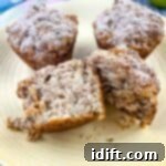 Wholesome Apple Date Walnut Muffins 14 A sliced Apple, Date and Walnut muffin on a plate with 2 muffins in the background.