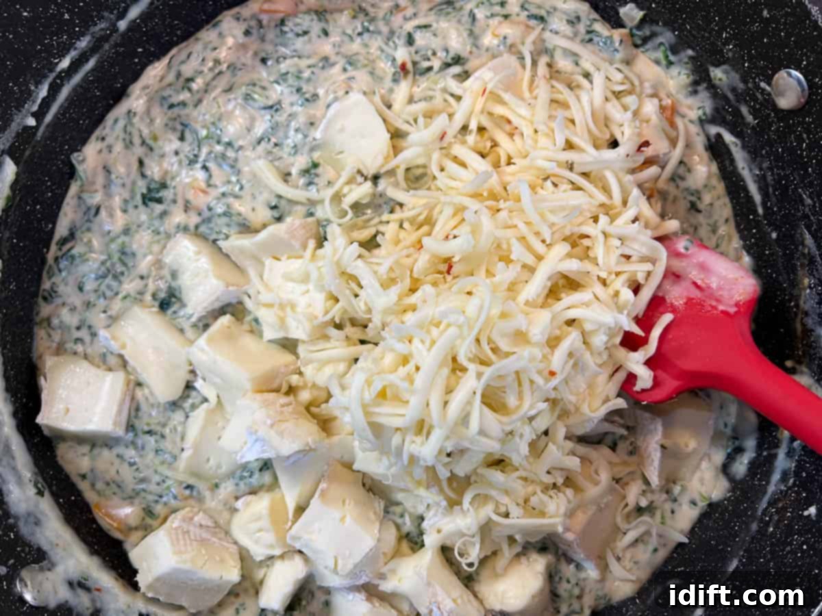 Mixing in the brie and cheeses into the spinach and cream sauce.