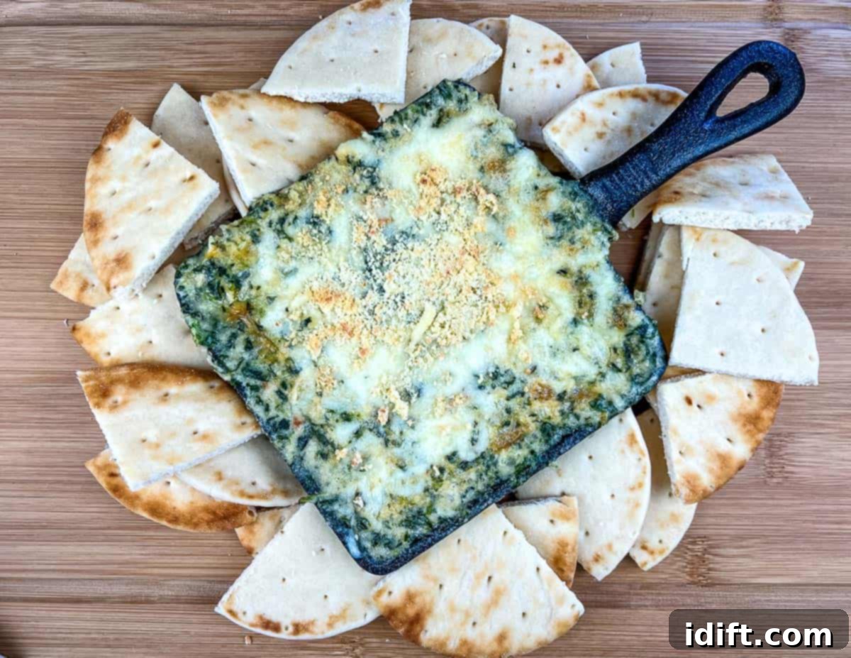 A top-down shot of Spinach and Brie Dip with pita wedges around it.