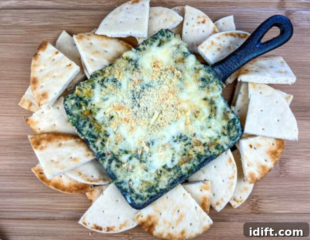 A top-down shot of Spinach and Brie Dip with pita wedges around it.