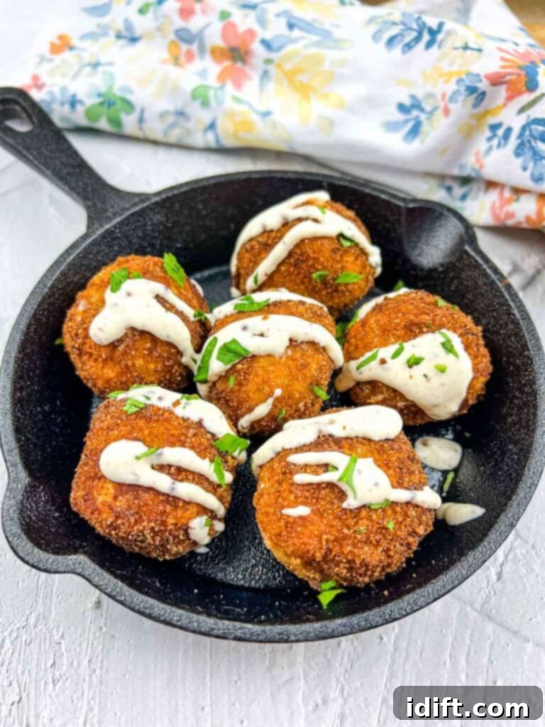 Savory Kraut Poppers 2 Sauerkraut balls in a black serving dish drizzled with mustard sauce.