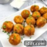 Savory Kraut Poppers 17 Sauerkraut balls on a plate with sauce in the background.