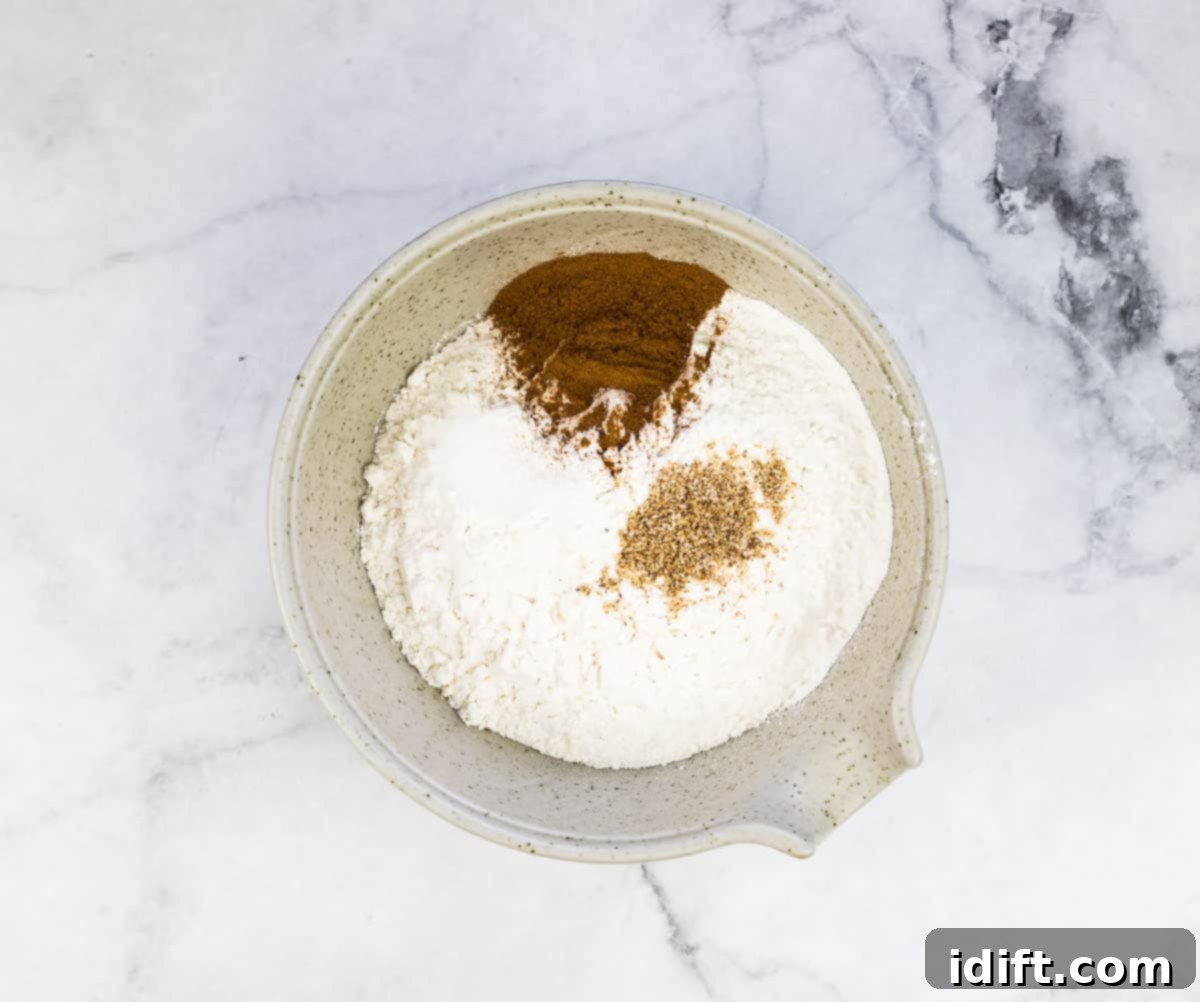 Dry ingredients like flour, cinnamon, nutmeg, and baking powder mixed in a bowl.