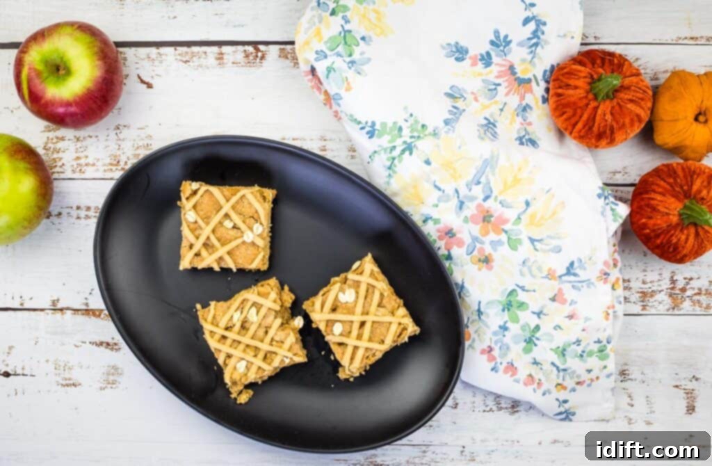 A top-down shot of 3 apple blondies on a black plate, with a fork, ready to be eaten.